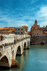 Tiberius bridge in Rimini on a background of blue sky with white clouds