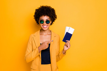 Poster - Portrait of positive cheerful brunette hair girl in sunglass hold passport point index finger recommend perfect summer tour voyage wear style blazer suit isolated over yellow color background