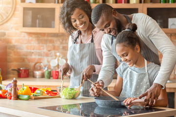 Wall Mural - Afro parents teaching their daughter how to cook