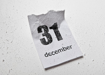 Snow-covered crumpled sheet of tear-off calendar with the date December 31