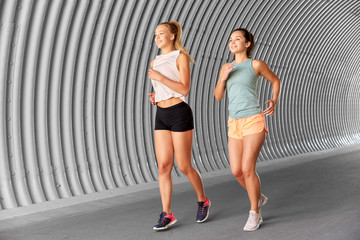 fitness, sport and healthy lifestyle concept - young women or female friends running outdoors