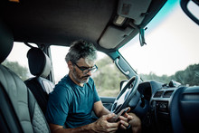 Mature, Man Sitting In His Off-road Vehicle Checking His Smartphone