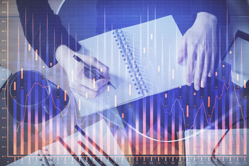 Forex chart hologram on hand taking notes background. Concept of analysis. Multi exposure