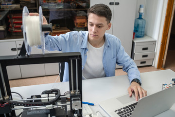 Student setting up 3D printer, using laptop