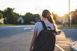 Teen girl depressed/sad at sunset in a parking lot while wearing a backpack and holding binders.