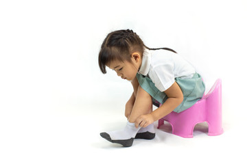 Wall Mural - Little kid practice put on the socks and shoes to dressing by herself. Learning to do activity daily living help the kids developt their self esteem and confident.Picture isolated on white background.