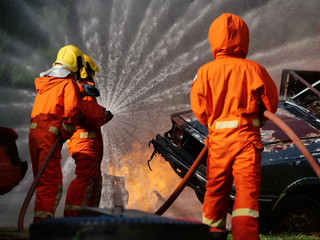 Wall Mural - firefighter spray water to fire burning car workshop fire training