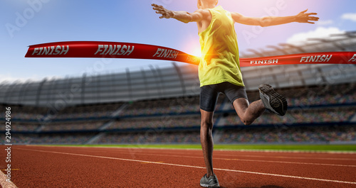 Fotomural Winning young male Athlete crosses the finish line.