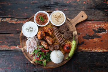 Mixed turkish kebab plate with rice, vegetables and dip sauces isolated on rustic wooden background