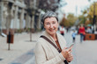 © Nana_studio - Portrait of a beautiful senior woman. Happy senior woman on the city streets using cellphone.