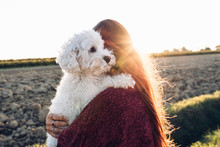Woman Hugging Her Dog At The Field At Sunset