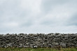 © Mint Images - View of old dry stone wall under a cloudy sky.