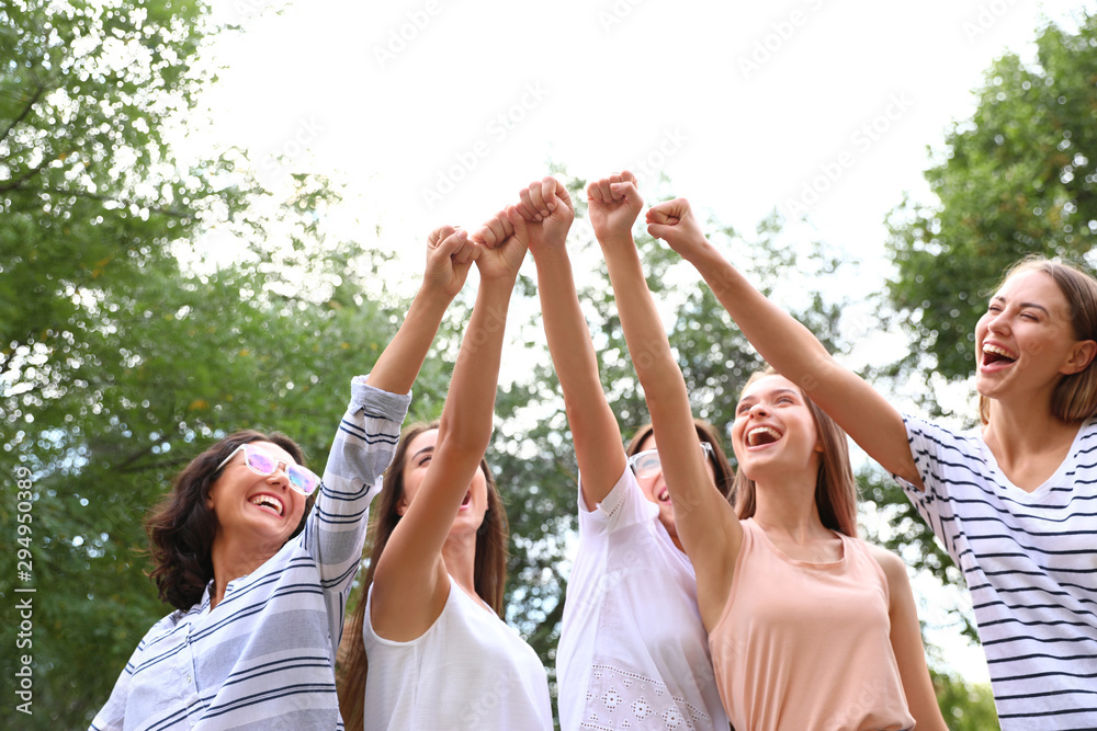 Happy women raising hands outdoors. Girl power concept - obrazy, fototapety, plakaty 