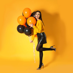 Wall Mural - Beautiful woman with balloons on yellow background. Halloween party