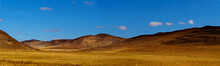 Panorama View Of Vast Grassland, Landscape With Mountains And Blue Sky