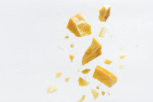 Parmesan Cheese Flying In Different Directions With Crumbs On A White Background With Space For The Text.