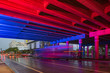 Fast bus passing under a bridge lit in blue and red neon lights Miami Design District
