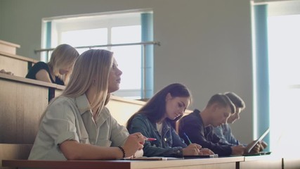 a group of male and female students in a large auditorium of the university listen to a lecture by a