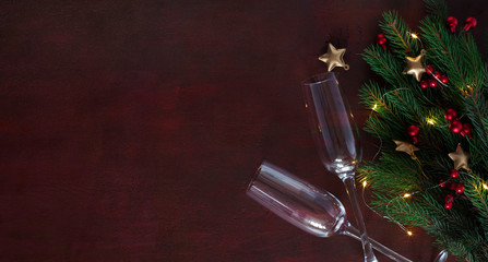 Sticker - Fir branch with Christmas decorations and two glasses on dark-red wooden table with empty space for text or image. Flat lay.