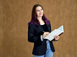 Studio portrait of a pretty brunette student girl with long hair in a jacket on a beige background. Smiling at camera with emotions in various poses.