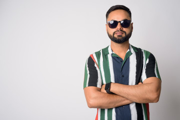 Portrait of young handsome bearded Indian man with arms crossed