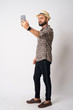 Full body shot of young bearded Indian man taking selfie
