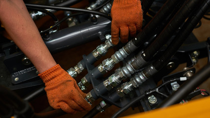 Low key photo of hydraulic pipes maintenance on heavy industry machine.