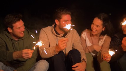 Wall Mural - celebration, holidays and people concept - happy friends with sparklers at night outdoors