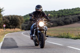 Young man biker having fun driving the empty highway on a motorcycle tour journey.