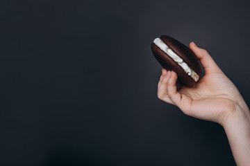 Poster - Close up Traditional chocolate and Pumpkin Whoopie pies filled made with vanilla cream in woman hand