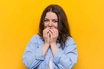 Wall Mural - Young curvy plus size woman laughing about something, covering mouth with hands.