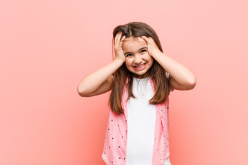 Sticker - Cute little girl laughs joyfully keeping hands on head. Happiness concept.