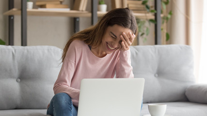 Wall Mural - Cheerful girl laughing watching funny online video on laptop