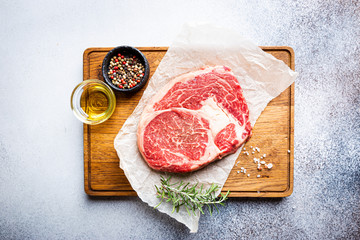 Raw fresh meat Ribeye Steak and seasonings on light background, top view with copy space