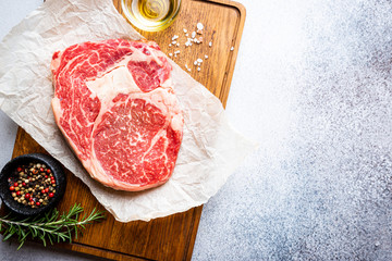 Raw fresh meat Ribeye Steak and seasonings on light background, top view with copy space