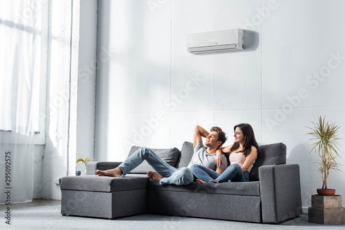 Fotomural attractive girlfriend and handsome boyfriend sitting on sofa and looking away