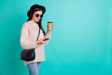 Poster - Portrait of cheerful lady use her phone follow blogs wear stylish trendy vintage jumper denim jeans cap hat drink mug espresso isolated over teal turquoise color background