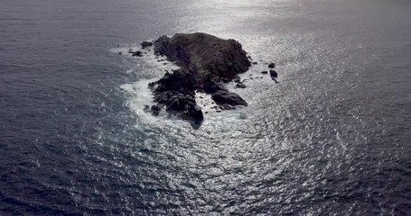 Canvas Print - Cinematic drone video of a small island with waves hitting the rocks at sunset dusk in Saint Martin Sint Maarten