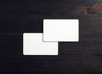 Two blank white business cards on wood table background. Mockup for branding ID. Flat lay.