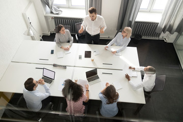 Overhead view busy multi racial office workers brainstorming at boardroom