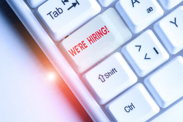 Conceptual hand writing showing We Are Re Hiring. Concept meaning process of reviewing applications and finding candidates White pc keyboard with note paper above the white background