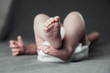 © Сергей Уланов - Newborn baby belly and legs in diaper, lying on white bed, top view, copy space