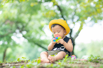 Adorable infant toddler baby boy playing in green park