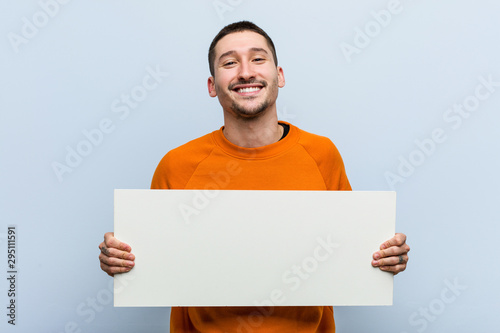 Fotografía Young caucasian man holding a placard happy, smiling and cheerful