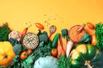 Organic vegetables, lentils, beans, raw ingredients for cooking on trendy yellow background. Healthy, clean eating concept. Vegan or gluten free diet. Copy space. Top view. Food frame