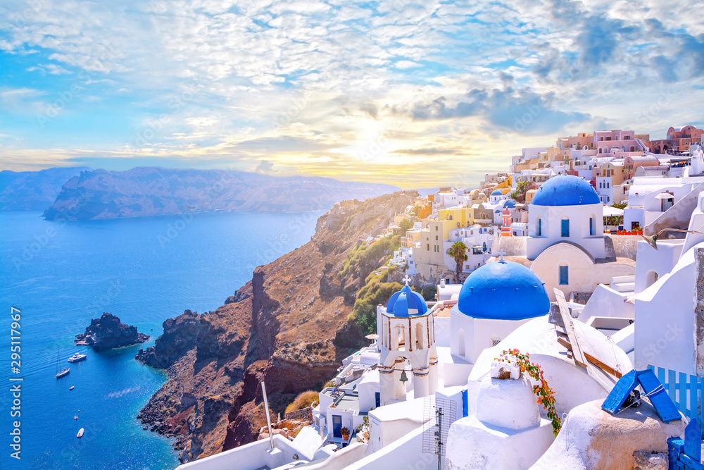 Beautiful Oia town on Santorini island, Greece. Traditional white architecture  and greek orthodox churches with blue domes over the Caldera, Aegean sea. Scenic travel background. - obrazy, fototapety, plakaty 