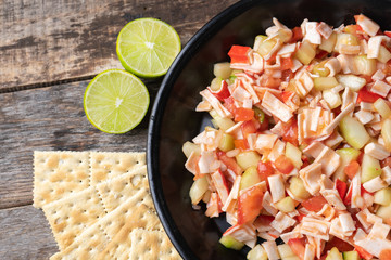 Surimi crab ceviche with cucumber and tomato on wooden background