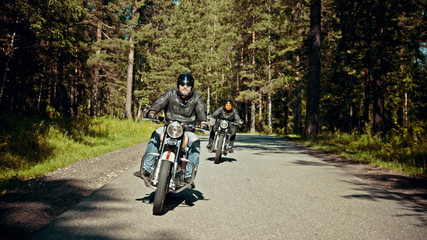 Two bikers are on their bikes riding too fast on the road