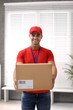 © New Africa - Young courier holding parcel indoors. Delivery service