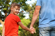 © New Africa - Little boy and his father holding hands outdoors. Family weekend
